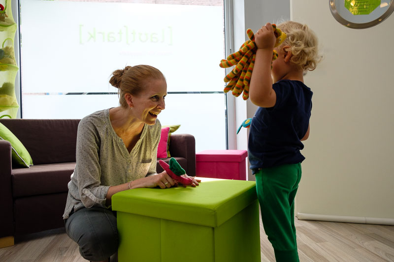 Therapeutin und Kind spielen lachend mit Handpuppen